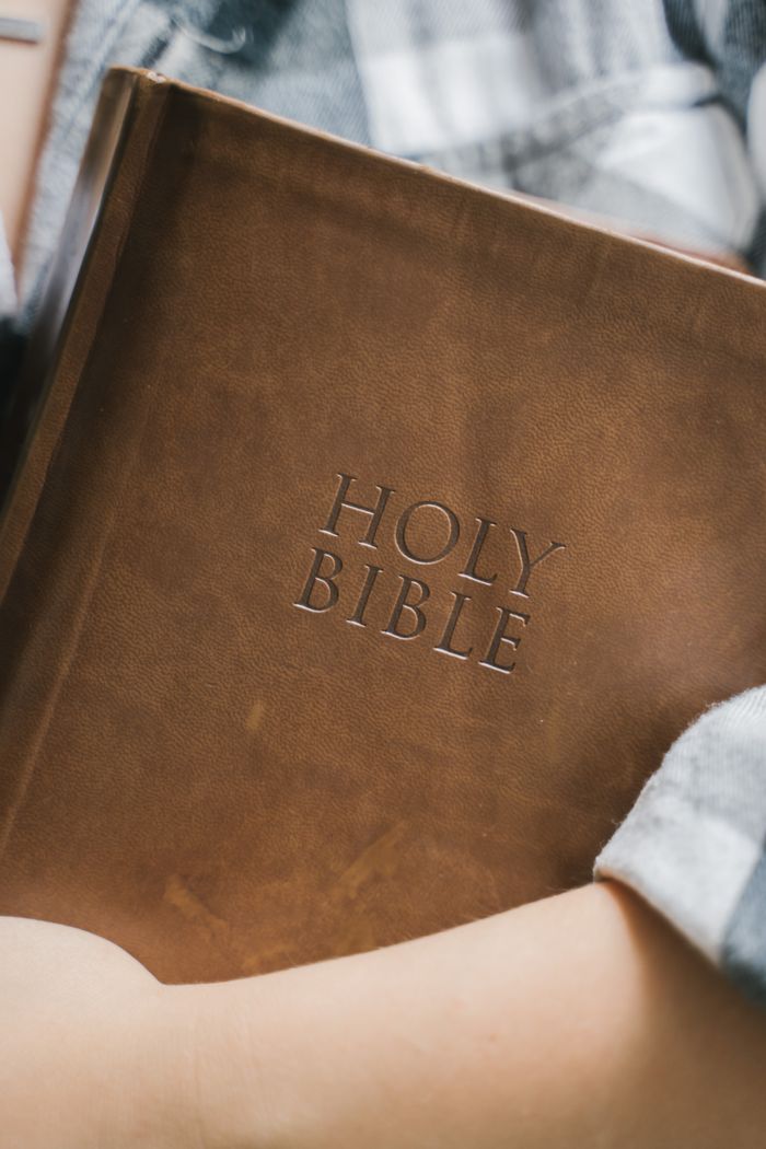 about-img A close-up shot of a leather-bound Holy Bible held in someone's hands, emphasizing faith and spirituality.